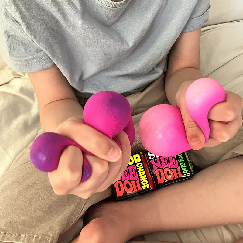 A person holding several colorful, stretchy Colour Changing NeeDoh balls in their hands above a container of more stress balls.