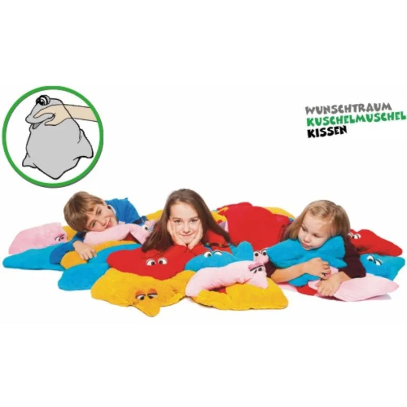 Three kids relax on vibrant star cushions with eyes, as an inset shows a hand holding a compactly folded cushion. Ideal as a storytelling companion or sensory toy, the German text reads "Wunschtraum Kuschelmuschel Kissen." This is the Dream Cuddle Pillow Green.