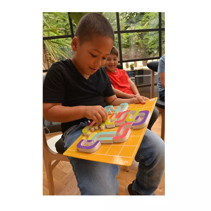 A young boy sitting at a table playing Magnetic Maze Kraze Game.