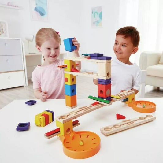 Two children problem-solving while playing with a Hape Music Motion toy at a table.