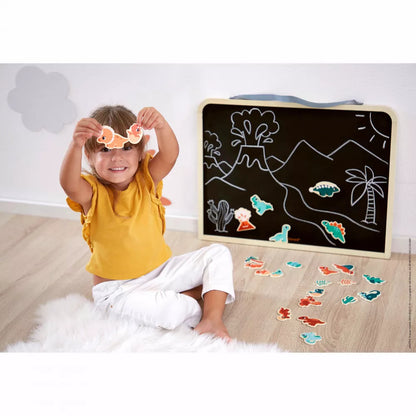 A little girl sitting on the floor in front of a Janod Dino - Dino Magnets 24 Pieces.