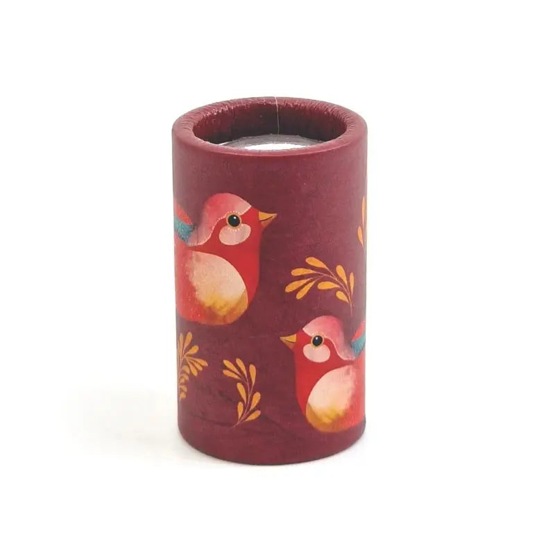 The Mini Kaleidoscope Birds is a cylindrical maroon candle holder featuring two red and yellow birds and yellow branches, creating a charming nature theme on a white background.