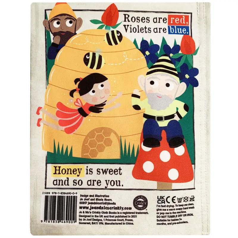 The Crinkly Cloth Book Gnomes and Fairies features a vibrant cover with a beehive, buzzing bees, gnomes in yellow-striped hats, a girl in pink, and magical flowers. The cover reads: "Roses are red, Violets are blue. Honey is sweet and so are you.