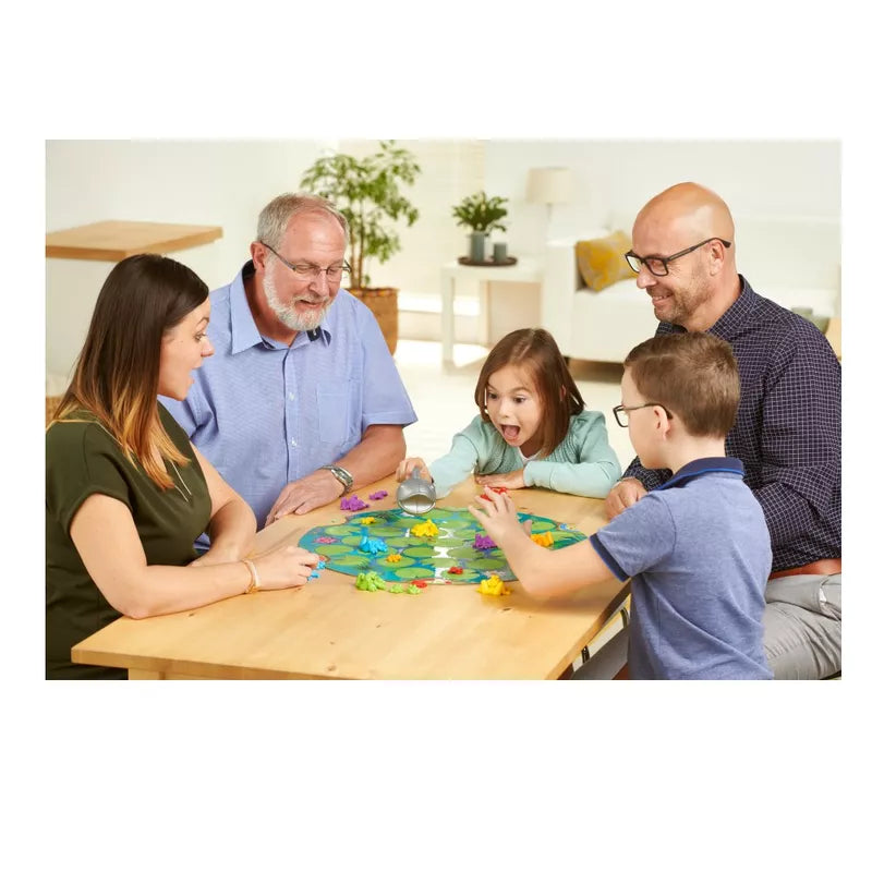 a family sitting around a table playing SmartGames Froggit.