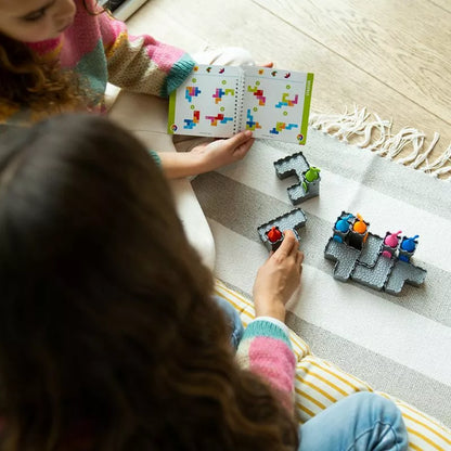 Two girls playing with SmartGames Tower Stacks puzzle pieces on the floor, building a vertical castle.