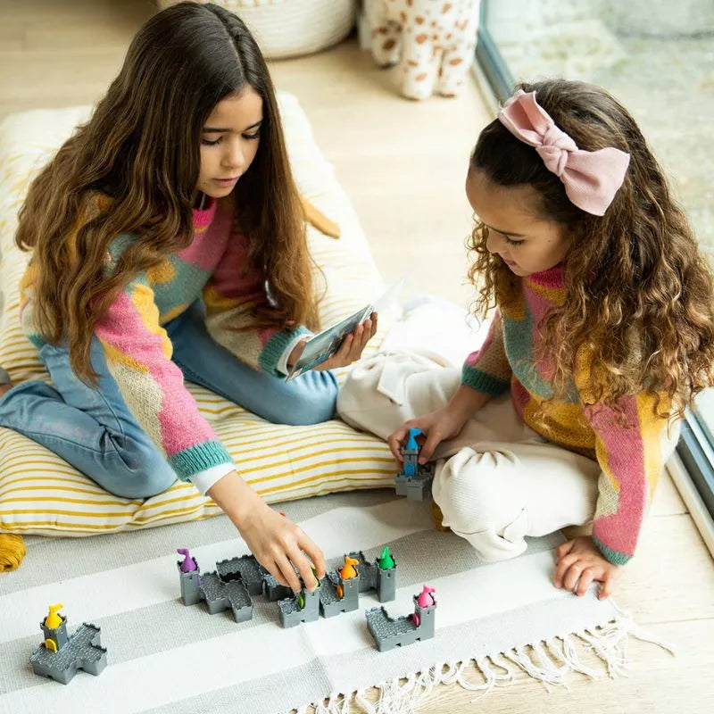 Two girls solving puzzles with SmartGames Tower Stacks on a rug.