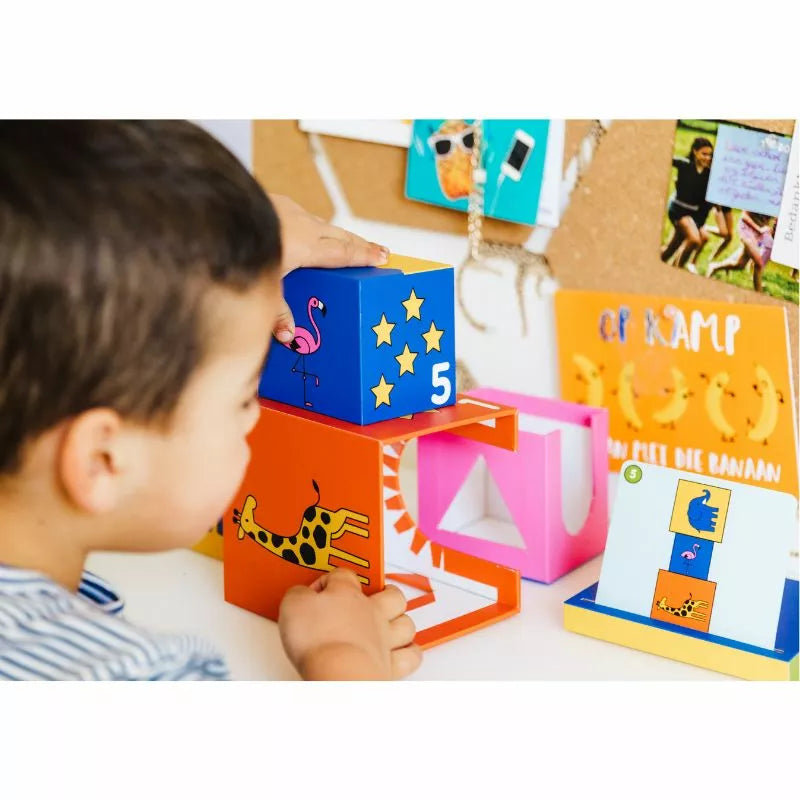 A young boy is playing with a set of SmartGames Peek-A-Zoo blocks.