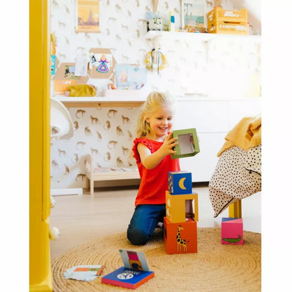 a young girl playing with SmartGames Peek-A-Zoo blocks in her bedroom.
