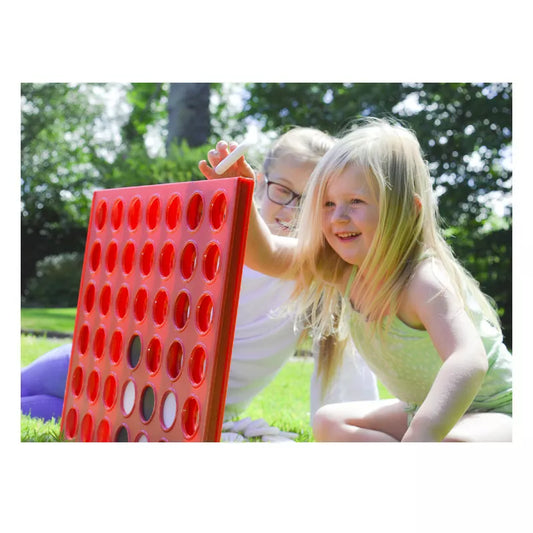 Two young girls playing with a Giant Garden Game Four in a Row.