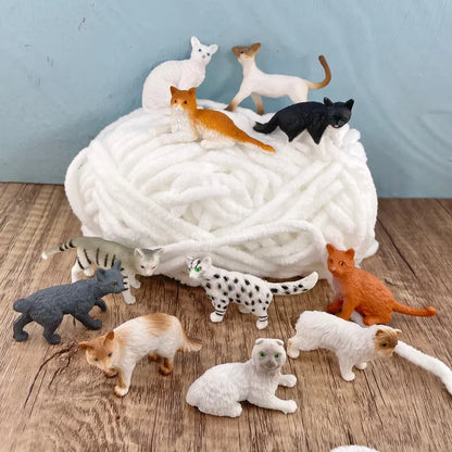 A collection of TOOB® Figurines Domestic Cats, in various colors and poses, displayed on and around a soft, white, coiled yarn against a light blue background.