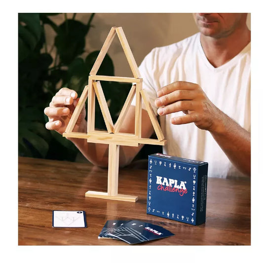 a man playing with a Kapla Challenge model of a house.