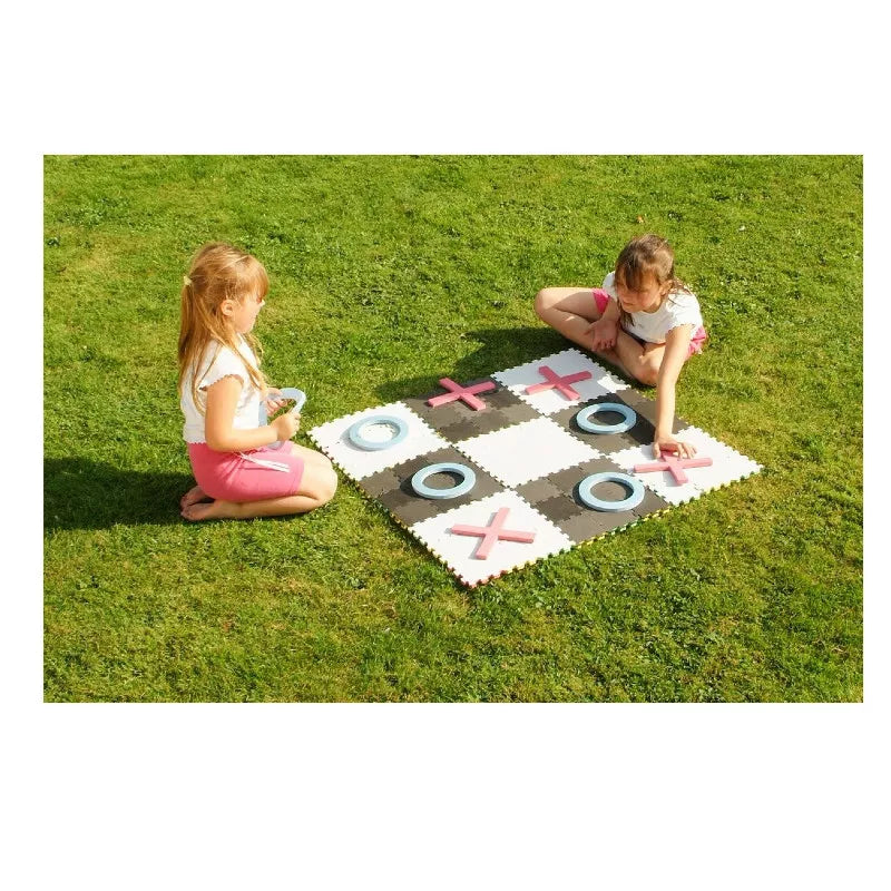 Two young girls playing 5 Big Games in One Set on a rug in the grass.