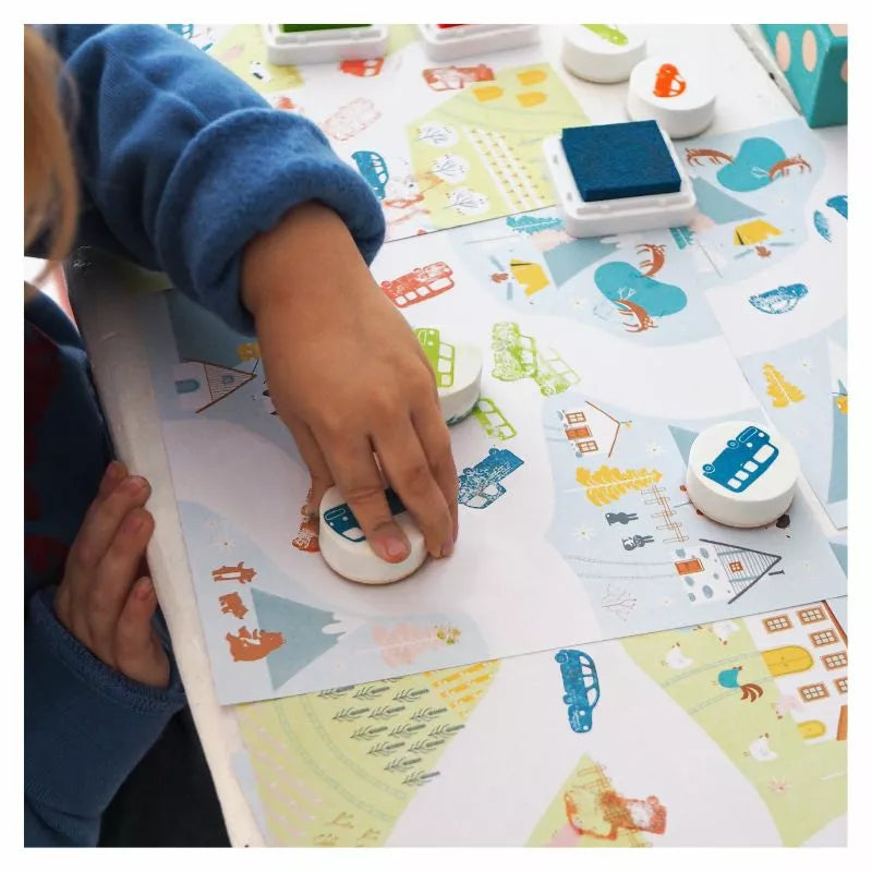 A child is using Djeco Stamps On the Road stamp pad on a paper.