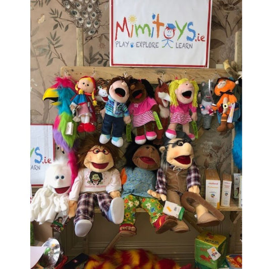 Colourful large hand puppets hanging on a shelf standing by a wall