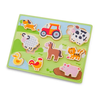 The New Classic Toys Chunky Farm Puzzle is a vibrant wooden toy that includes pieces shaped like various farm animals and objects—such as a dog, tractor, cow, sheep, horse, cat, duck, rooster, and pig—set against a delightful green background depicting a charming farm scene.