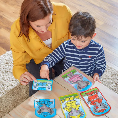 A woman in a yellow blouse and a child in a striped shirt are seated on the floor with a wooden table, playing an Orchard Toys Dress Up Nelly card matching game with animal themes. A beige rug partially covers the flooring.