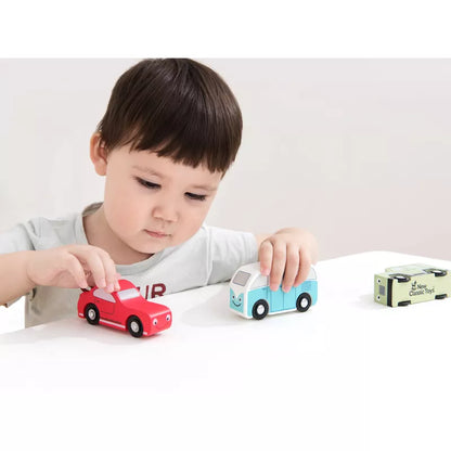 A young boy, who is a car lover, is engaged in role play as he plays with the New Classic Toys Vehicles set of 3 on a table.