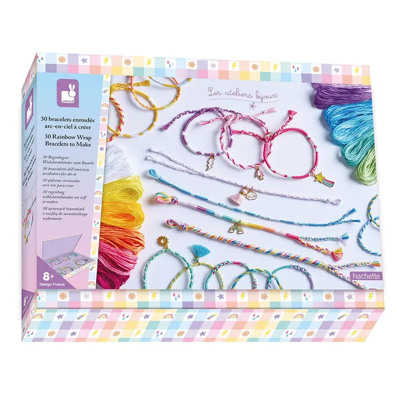 The Janod 30 Rainbow Wrap Bracelets To Make kit is shown, featuring colorful rainbow-colored threads and completed friendship bracelets. The box includes 30 designs for creating wrap bracelets and is intended for ages 8 and up. The pastel packaging has a cheerful checkered pattern.