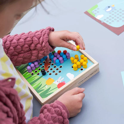 A little girl developing her colour recognition skills while playing with the Bigjigs Garden Peg Board game.