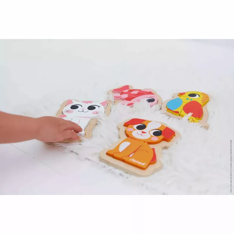 A toddler's hand reaching for Janod 4 Progressive Puzzles - Pet placed on a fluffy white rug.