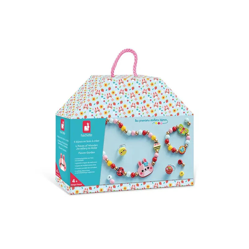 A colorful, house-shaped box contains the "Janod 4 Pieces of Wooden Jewellery - Flower Garden" set by Hachette. This creative toy for kids includes various beads and accessories, such as a cute bunny bead and an array of colorful flowers, perfect for creating bracelets and necklaces in this delightful children's jewelry kit.