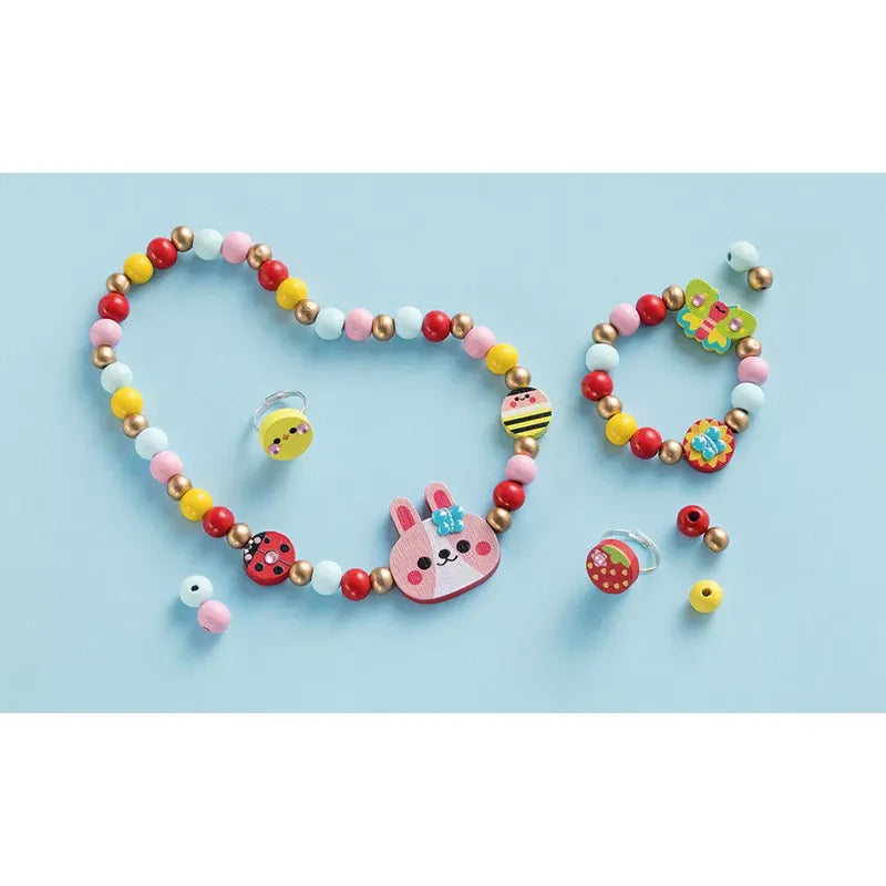 A set of colorful beaded jewelry on a light blue background, featuring the Janod 4 Pieces Of Wooden Jewellery - Flower Garden, which includes a necklace and bracelet adorned with different shaped beads like ladybugs, a bunny, and flowers. The delightful children's jewelry kit also comes with several loose beads for endless fun and creativity.