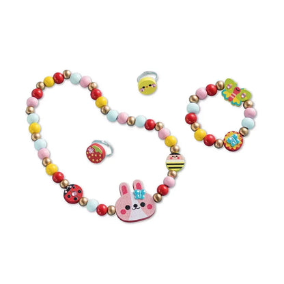 The Janod 4 Pieces Of Wooden Jewellery - Flower Garden is a vibrant and creative children's jewelry kit including a beaded necklace with a pink rabbit pendant, a matching beaded bracelet, and three rings featuring designs of a strawberry, bumblebee, and butterfly. This delightful toy for kids uses colorful pastel wooden beads.