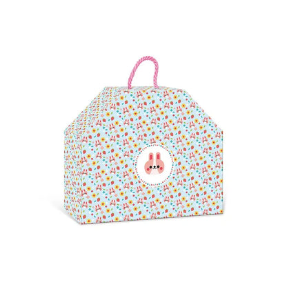 A colorful gift box with an adorable pattern of small, variously colored shapes. The box has a pink handle on top and a circular design featuring a pink bunny face in the center on the front side. Shaped like a house, it can also store the Janod 4 Pieces Of Wooden Jewellery - Flower Garden toy or even other children's jewelry kits.