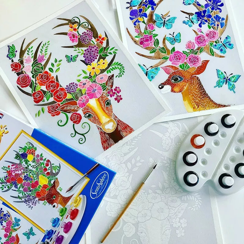 A set of Sentosphere Aquarellum Enchanted Deers paintings with vibrant colors and brushes on a table.