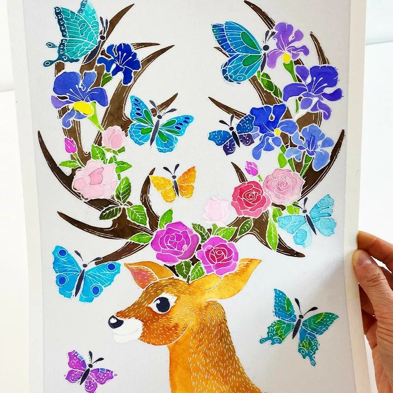A hand holding a painting created using the Sentosphere Aquarellum Enchanted Deers technique, depicting a deer with flowers and butterflies.