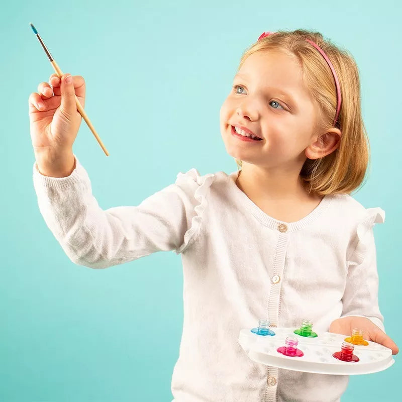 A little girl holding a Sentosphere Aquarellum Junior Princesses paintbrush and palette.