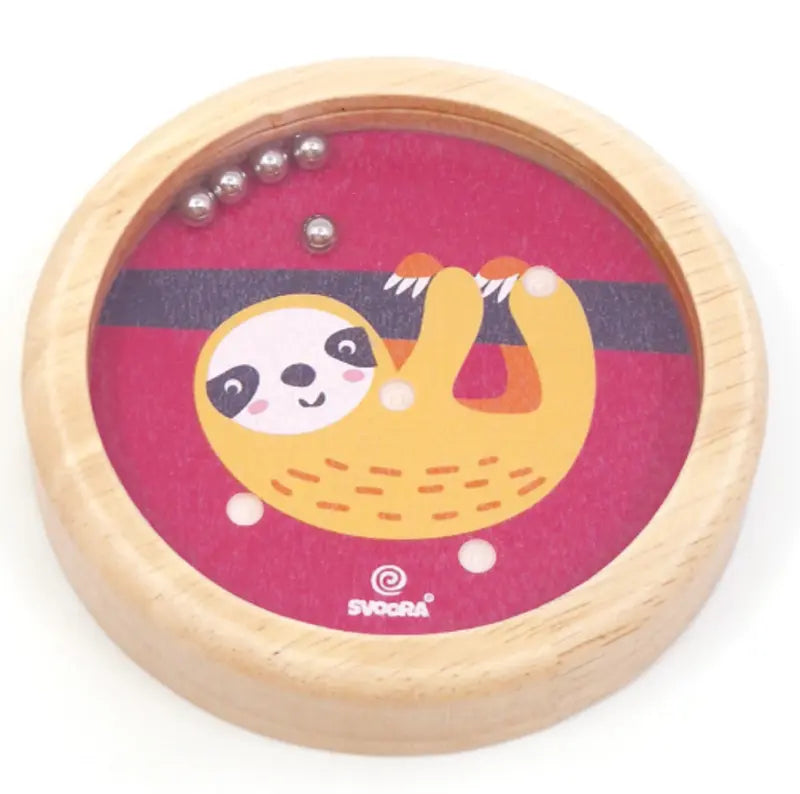 The Wooden Balance Game Sloth is a round wooden toy with a cartoon sloth on a red background. Roll small metal balls into holes for fun—perfect as a travel game for kids.