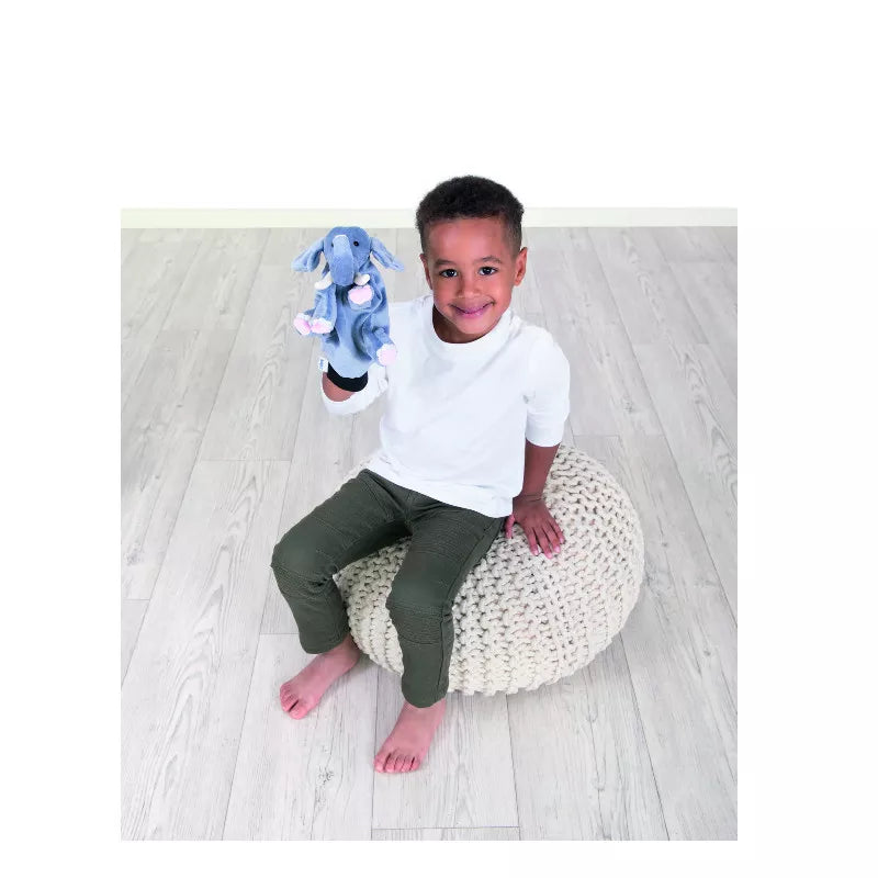 A young boy sitting on a bean bag chair holding a Beleduc Hand Puppet Elephant.