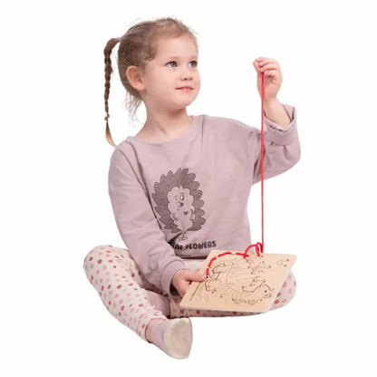 A little girl sitting on the floor playing with Bigjigs Lacing by Numbers - Dinosaurs by Bigjigs.