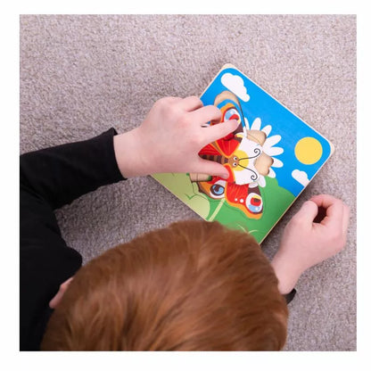 A child is playing with a Bigjigs Lifecycle Puzzle Butterfly on the floor.