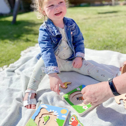 A little girl playing with a Bigjigs Lifecycle Puzzle Ladybird toy on a blanket.