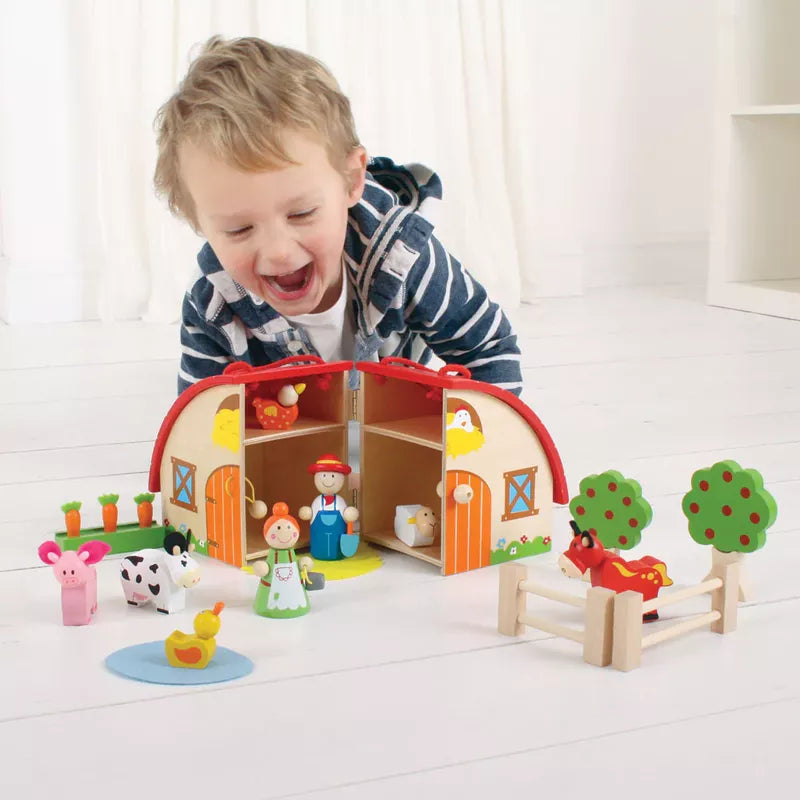 A young boy playing with a Bigjigs Mini Farm Playset on the floor.
