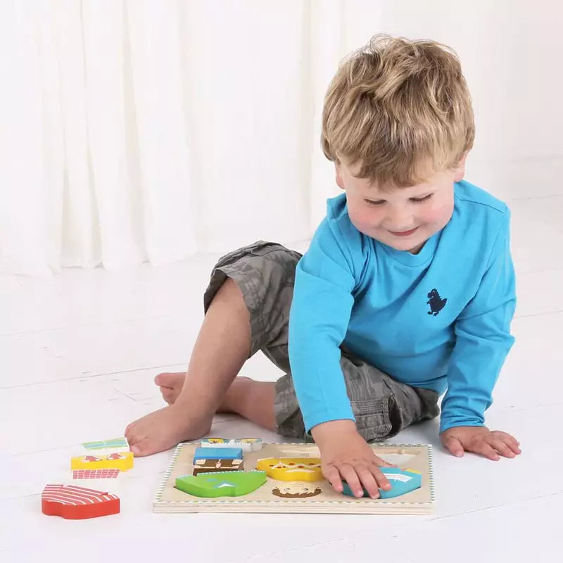 A young boy playing with his Bigjigs Dressing Boy Puzzle toys on the floor.