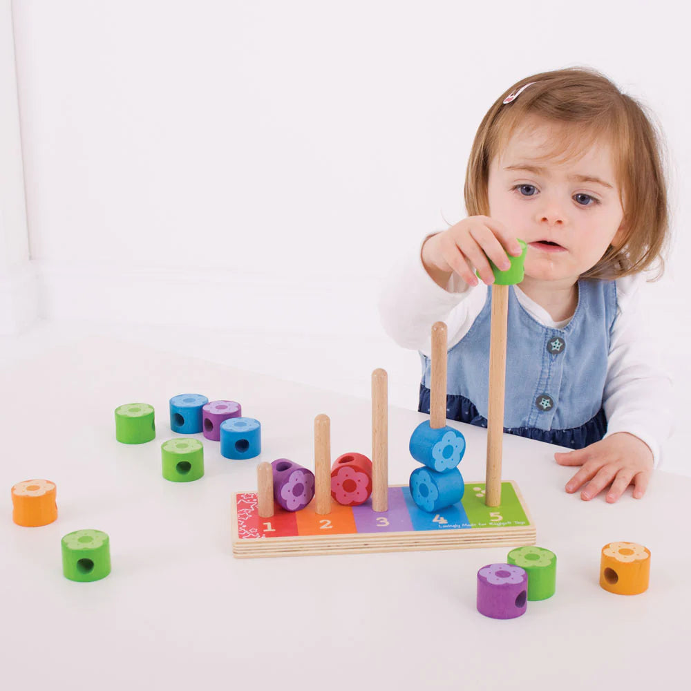 A little girl playing with a Bigjigs Flower Stacker Wooden Toy set.