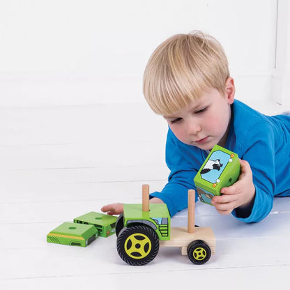 A young boy playing with a Bigjigs Stacking Tractor on the floor, developing his fine-motor skills.