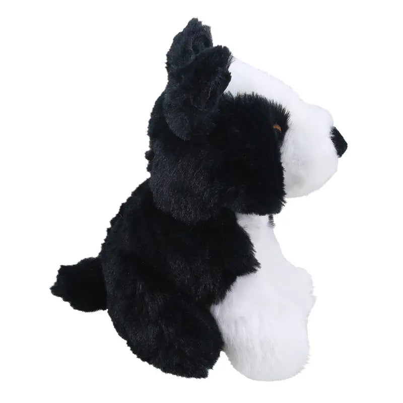 The Wilberry Eco Mini Border Collie is a black and white plush toy dog, sitting upright and facing right, made from eco-friendly recycled materials.