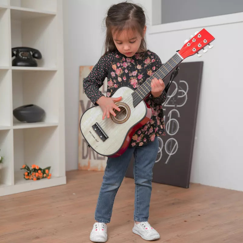 A little girl is playing with a New Classic Brown Guitar Deluxe.