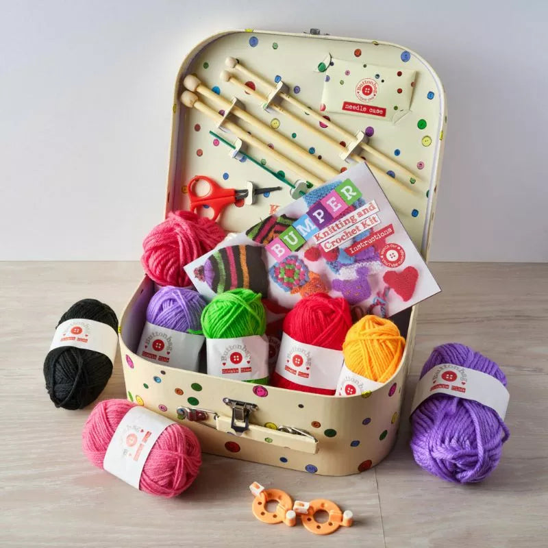 A suitcase full of Buttonbag Bumper Learn to Knit and Crochet, knitting needles, and materials to learn to knit.