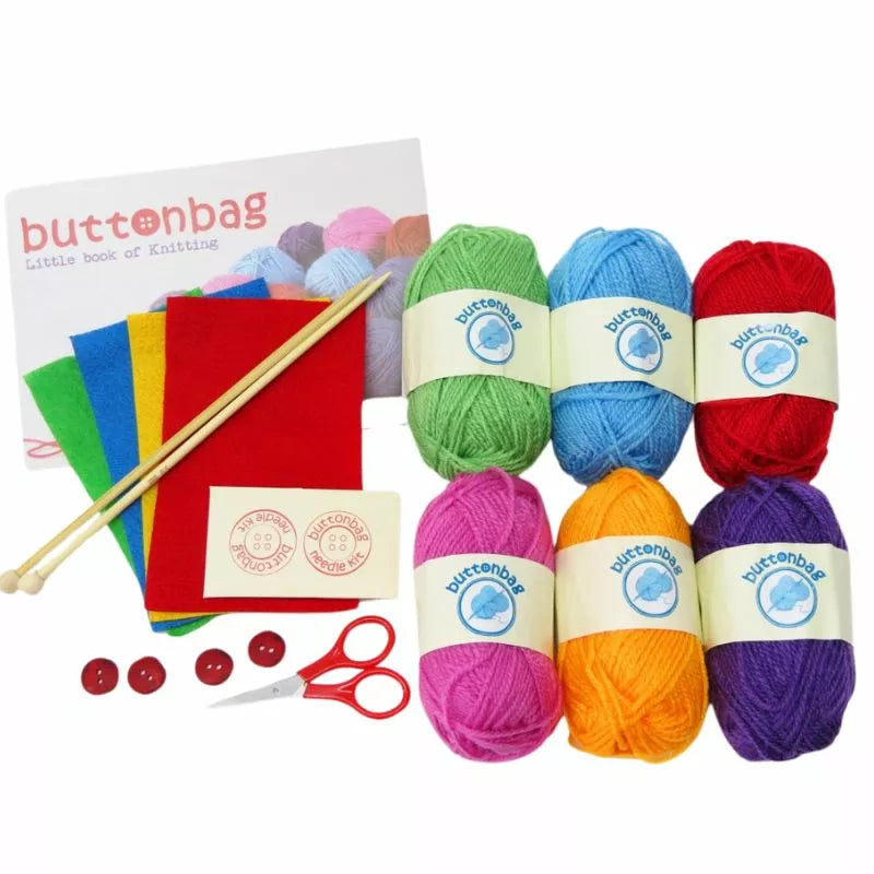 A Buttonbag Learn to Knit Suitcase Kit including yarn, scissors, and knitting needles to learn.