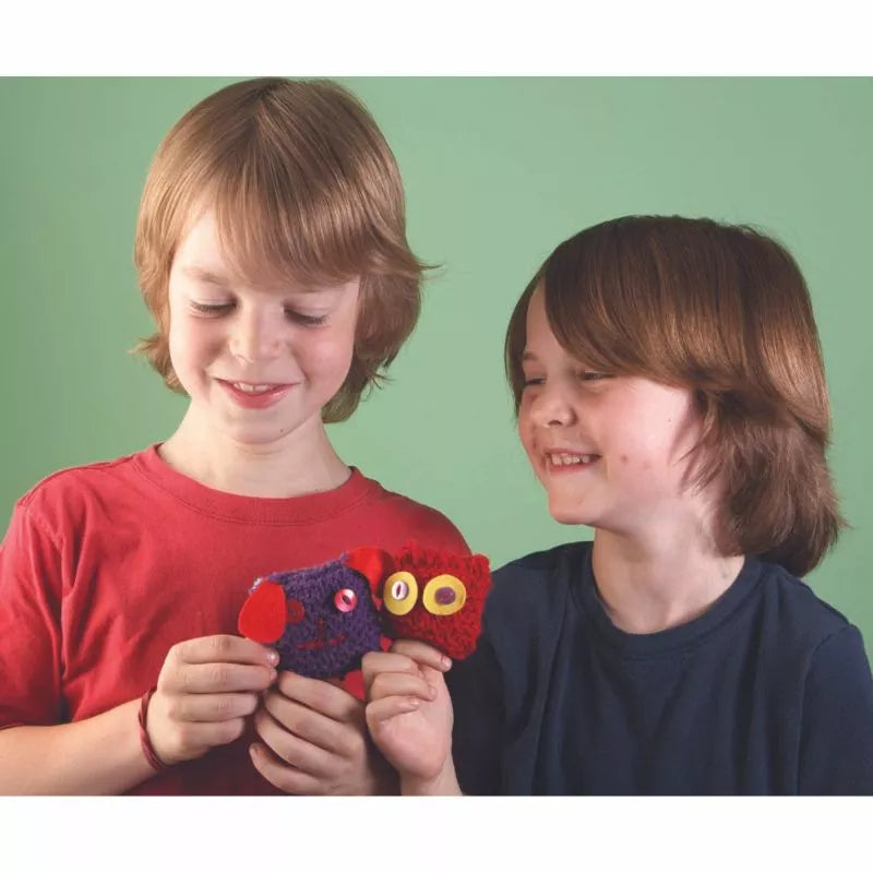 A couple of boys holding up toys they learned to knit from a Buttonbag Learn to Knit Suitcase Kit.