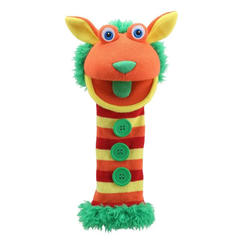 The Puppet Company Sockette Puppet Buttons features a colorful, goofy-faced puppet with a bright orange and yellow head, green fuzzy hair, blue eyes, and a wide open mouth. Its long neck is striped in red and yellow, adorned with three green buttons sewn down the front. The base of this moving hand puppet is also green and fuzzy.