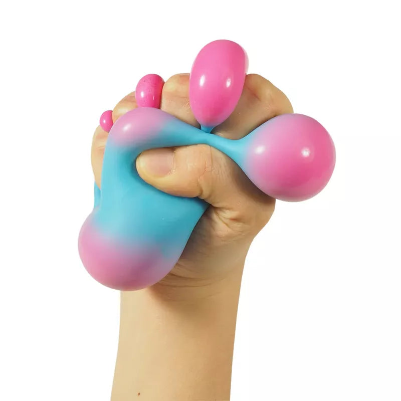 Sentence with product name: A hand squeezing a Hypercolor NeeDoh, with pink and blue hues blending together, and parts of the fidget toy bulging between fingers.