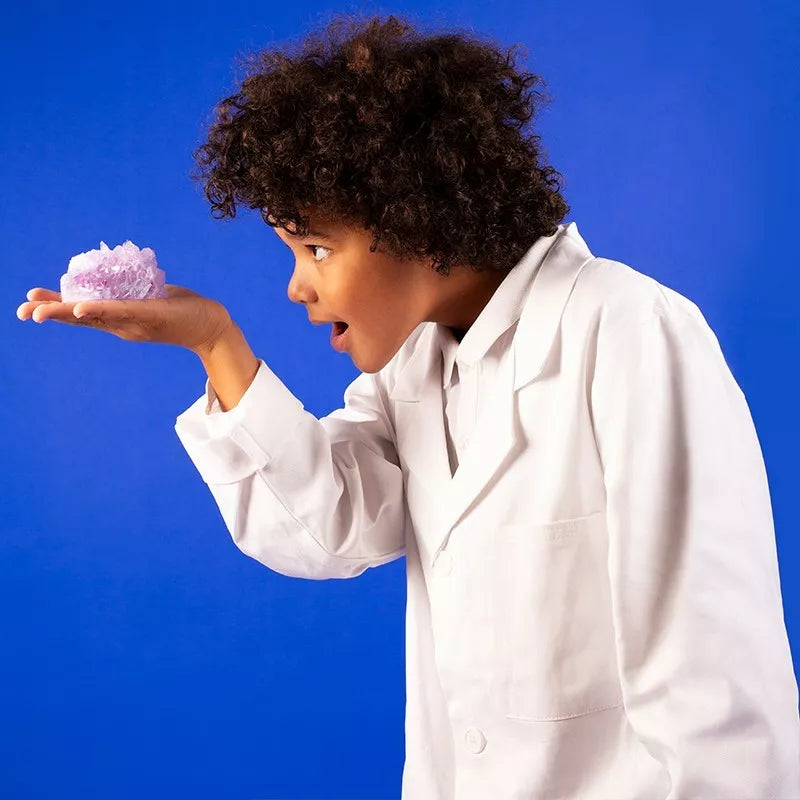 A girl in a lab coat is holding a Sentosphere Chemistry of Crystals grown through crystallization.