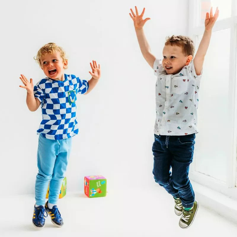 Two young boys jumping in a white room during a CubeFun Exercise DUE 2024 game.