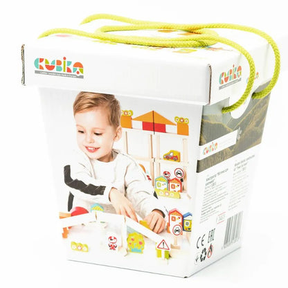 The image shows packaging for a children's toy set by "Cubika." The box is white with colorful illustrations and images of the "Cubika ECO Wooden Blocks Construction City" toy set, featuring toddler wooden blocks and a smiling child. Green rope handles on the top make it easy to carry, while the packaging promotes imaginative play. Safe water-based paints are highlighted in the product information printed on the sides.